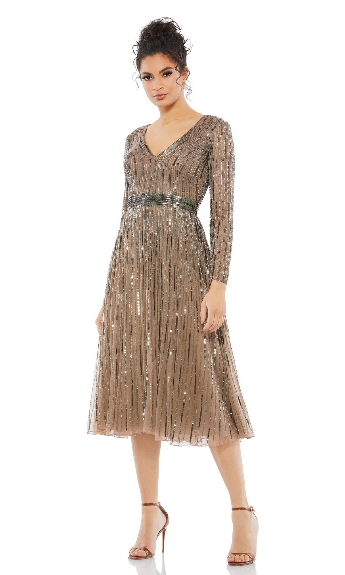 A woman wears the Short Semi-Formal Dress 5528 by Mac Duggal, an A-line tea length piece featuring metallic sequins, a belted waist, long sleeves, and a V-neckline, styled with strappy high-heeled sandals.